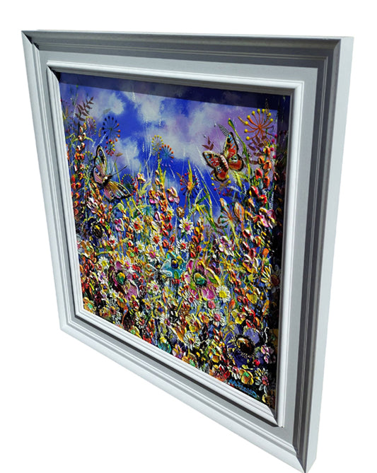 Framed floral artwork showing a colorful field of flowers under a blue sky, presented in a white frame against a light gray background.