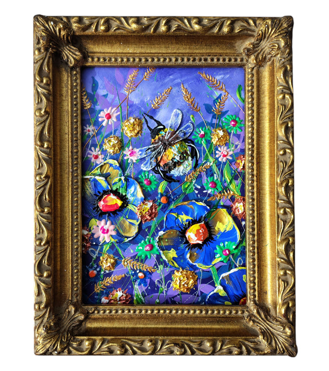 A framed colorful painting featuring a bee among flowers and wheat, enclosed in an ornate gold frame on a white background.