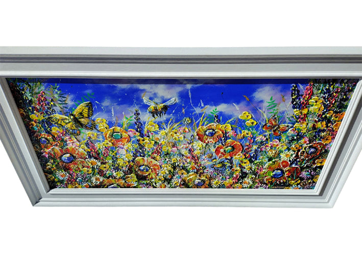 A rectangular framed painting depicting a vibrant wildflower meadow with colorful butterflies and bees under a bright blue sky, shown against a plain white background.