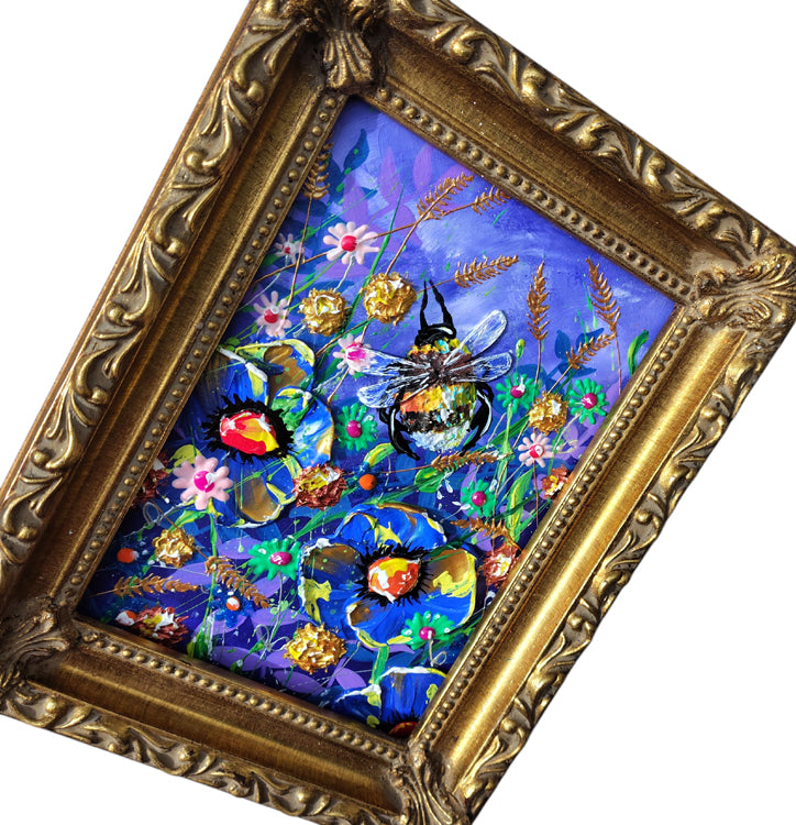 A framed colorful painting featuring a bee among blue flowers and green stems on a purple background, set in an ornate gold frame.