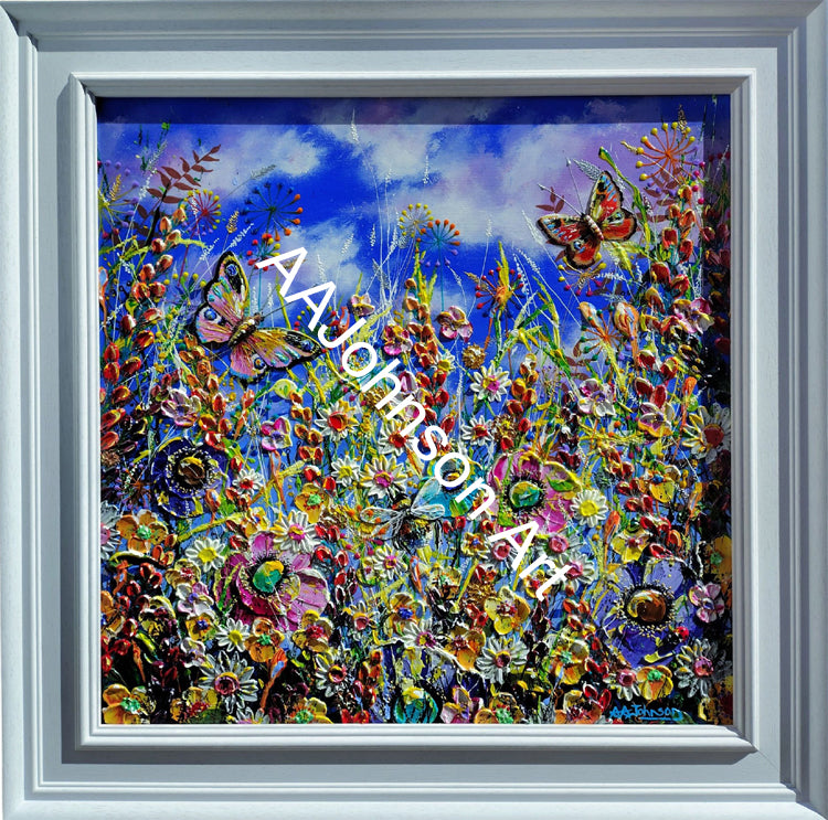 A framed square canvas painting depicting a vibrant, colorful wildflower meadow under a blue sky with butterflies. The artwork features thick impasto brushstrokes and is presented in a white  frame.