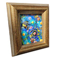 A framed floral art print featuring a vibrant blue background with colorful flowers and two bumblebees, enclosed in a distressed gold-toned wooden frame.